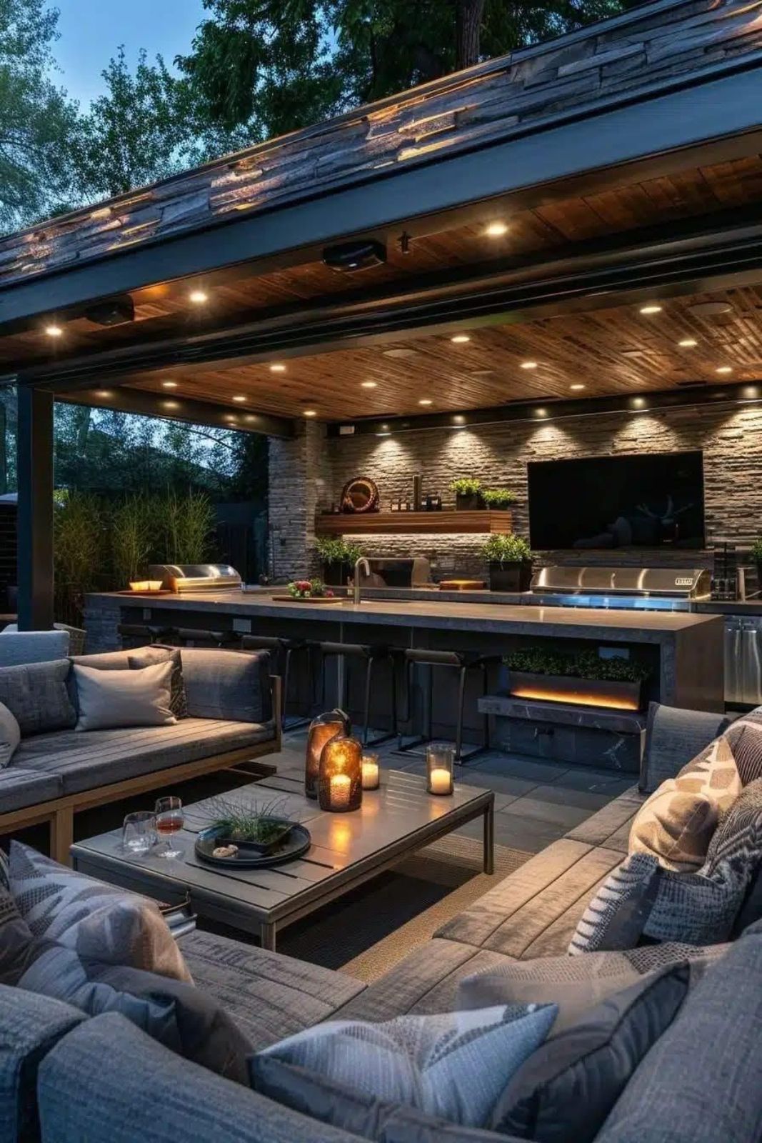 Outdoor covered patio with modern seating, fireplace, and TV.